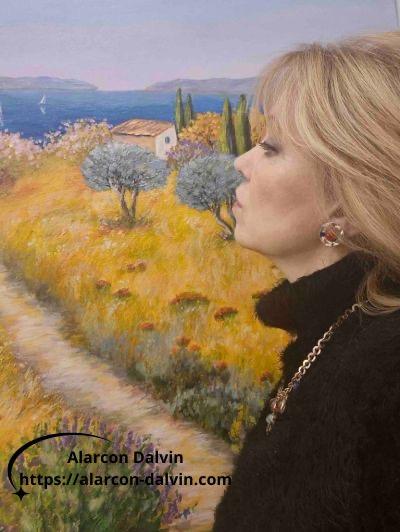 Danielle Alarcon Dalvin, artiste peintre contemporaine à Saint-Paul-de-Vence, debout devant une peinture figurative achevée dans son atelier, lumière provençale Côte d'Azur, technique acrylique et couteau