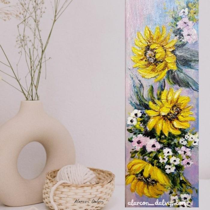 Tableau vertical de tournesols jaunes posé dans un espace décoré avec un vase de fleurs beiges et une corbeille en rotin, reflétant un esprit moderne et minimaliste.